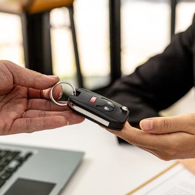 A person returning a car key to an employee for completing a car rental service.