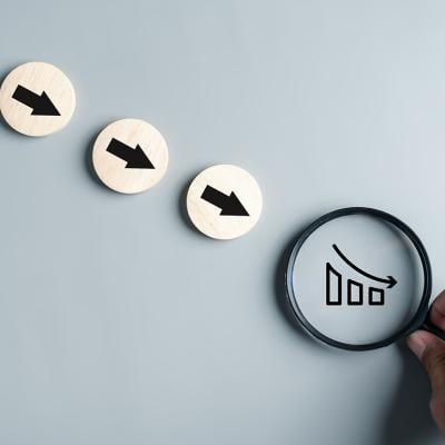 Downward arrows and a magnifier focused on a declining chart as a concept of inflation.