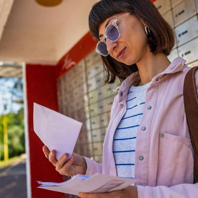 A young woman checking letters from mailbox.