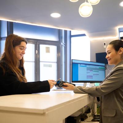 Patient making a contactless payment at a clinic's reception desk.