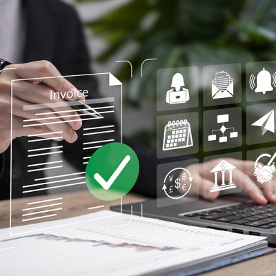 Automated invoice software graphics over a businessperson using a laptop.