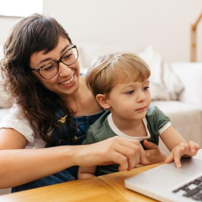 A mother and a son checking on a laptop in a living room.