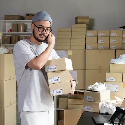 A male e-commerce shoe business owner on the phone while assembling orders.