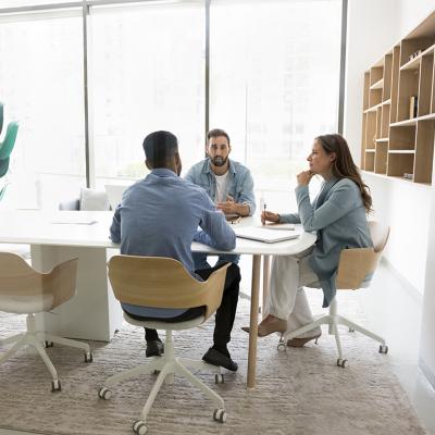 A three-member business team brainstorming inside a meeting room.