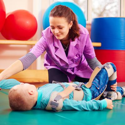 A pediatric therapist helping a young boy with a musculoskeletal therapy exercise.