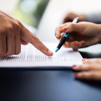 A pointing finger guiding the other person where to sign in a document.