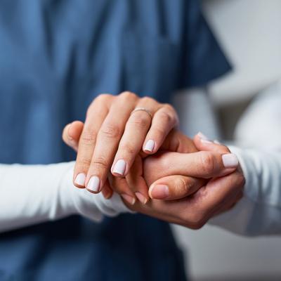 A nurse compassionately holding hand of a patient.