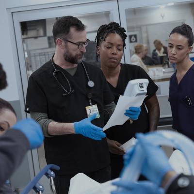 Noah Wyle, Ayesha Harris, and Alexandra Metz in a promotional still for season two, episode 13 of The Pitt.