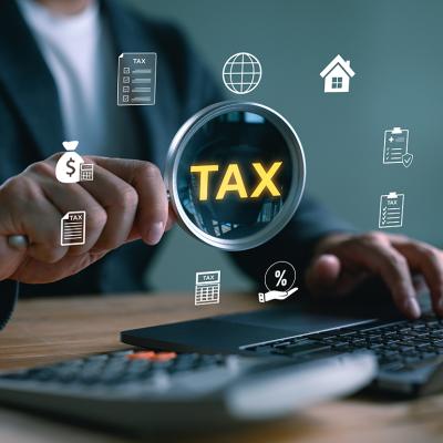 'Tax' and related graphics illustrated over a magnifying glass focusing on a computer as a concept of tax filing.