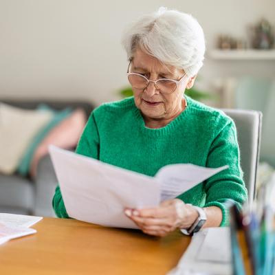 A senior woman sitting in the living room and doing paperwork.