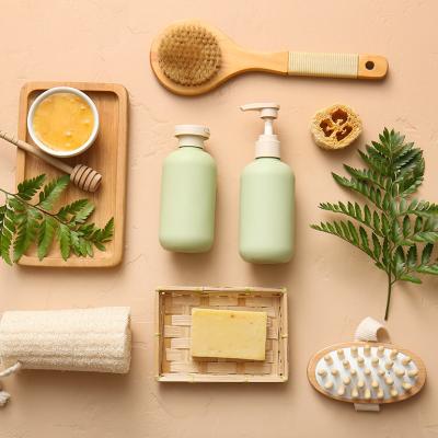 Soap, body scrub, brushes and bathroom essentials laid on a beige surface.