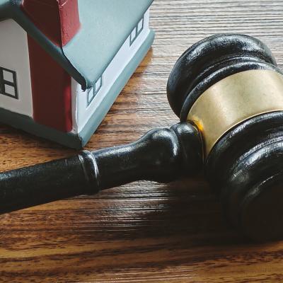 A miniature house and a gavel in a wooden surface.
