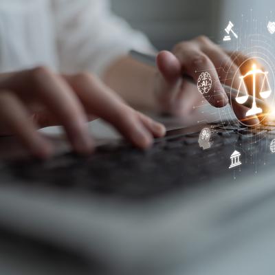 A person using a laptop that shows a futuristic justice scale with digital law interface.
