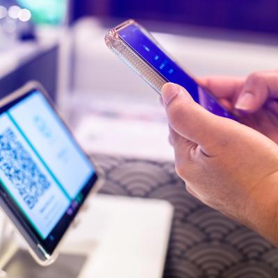 A person using a smart phone to scan a QR code from a smart device for a digital registration.