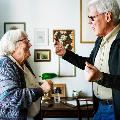 A senior couple dancing together at home.
