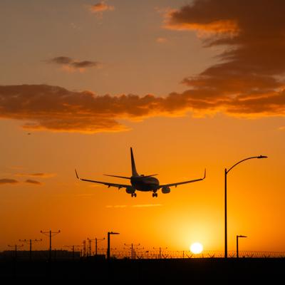 An airplane landing at Los Angeles International Airport during sunset in California, USA.