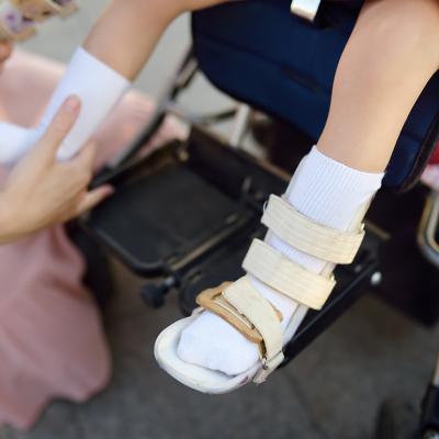 A mother helps her disabled daughter with putting on leg braces.