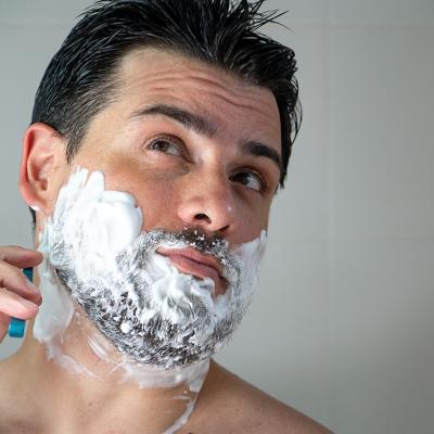 A young man shaving his beard.