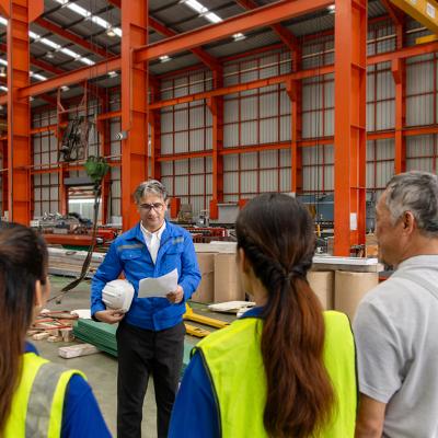 A supervisor leads his team for a briefing inside a manufacturing factory.