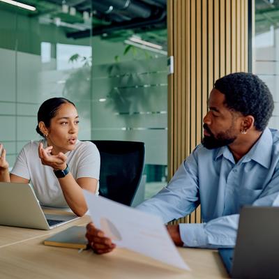 Two business colleagues engaged in discussion in a boardroom.