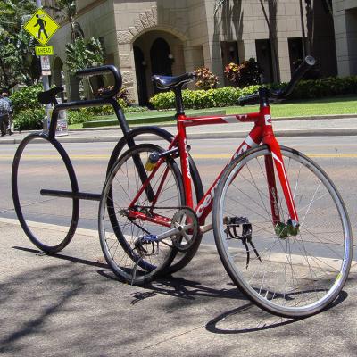 A red racing bicycle locked on a bicycle-shaped parking rack in Honolulu, Hawaii.