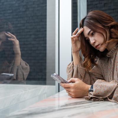 A person checking on her phone, while looking worried about something.