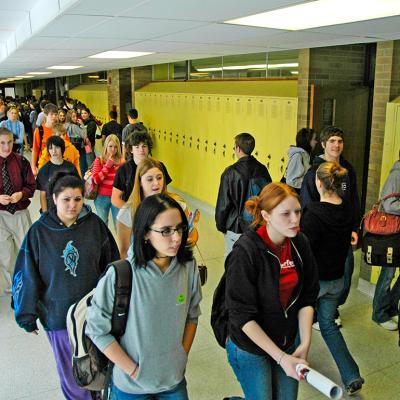 High school students walking along hallways.