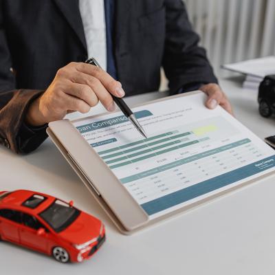 A loan officer showing a car loan comparison document to a client.
