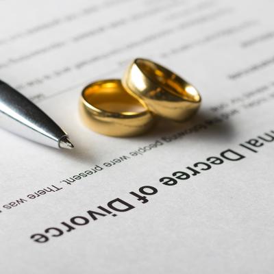 Marriage rings and a pen on top of a divorce decree form. 