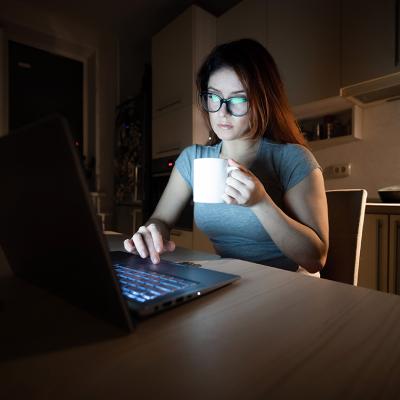 A young female professional working from a home's kitchen at night.