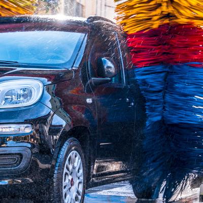 A car going through massive automated car wash brushes.