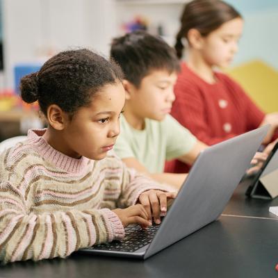 A group of children using laptops in a classroom.