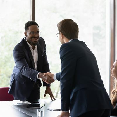Business partners shaking hands after securing a sales deal in an office.