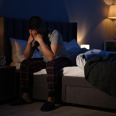 A man with his hands on his face after waking in the middle of the night.