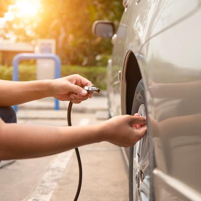 Man inflating car tires at a gas station.