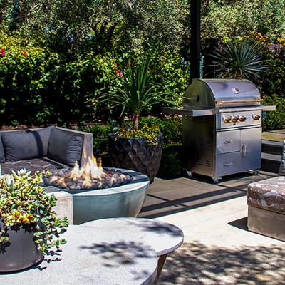 An outdoor entertainment space with gray sofas and a fire pit.