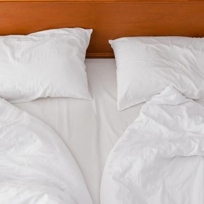 A view from above of an unmade bed with two duvets and white pillows.