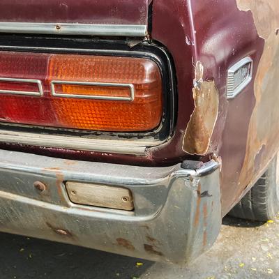 A close-up shot of the back of an old rusty car. 