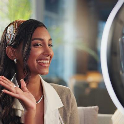 A young female influencer filming a vlog at home using a ring light and smartphone.