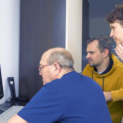 Senior parents using a computer at home guided by their adult son.