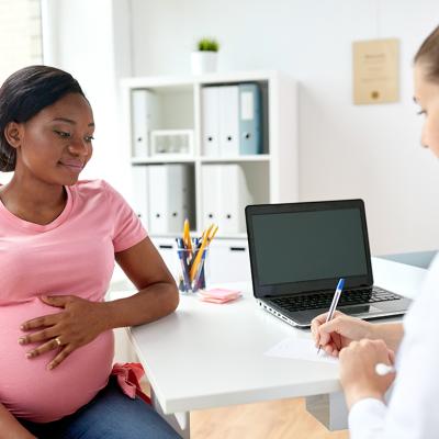 A pregnant black woman consulting with her doctor in a clinic.