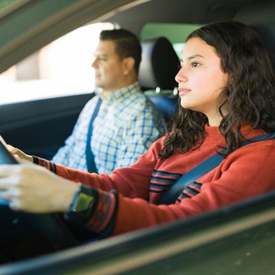 A teenage girl learning how to drive with her father.