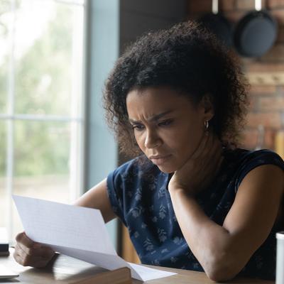A frustrated young woman at home reading a letter with bad news.