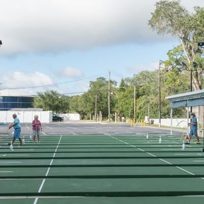 Older people playing shuffleboard at a resort.