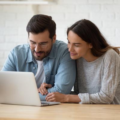 A married couple checking online accounts together in a laptop.