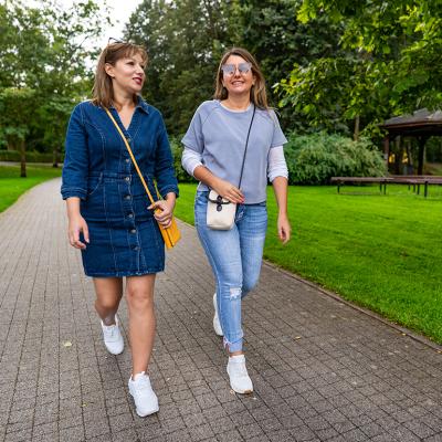 Two friends sharing stories while strolling in a city park. 