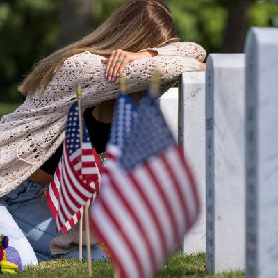 A young bridge grieving at a burial site of a family member in a military cemetery.
