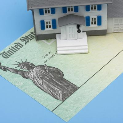 A miniature house placed over a U.S. tax refund check.