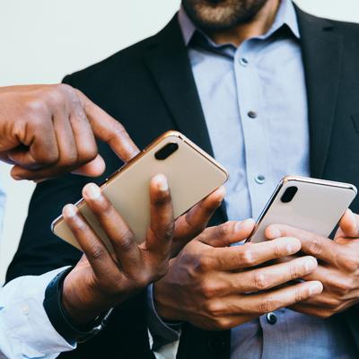 A business person showing an online post from his smartphone to a colleague. 
