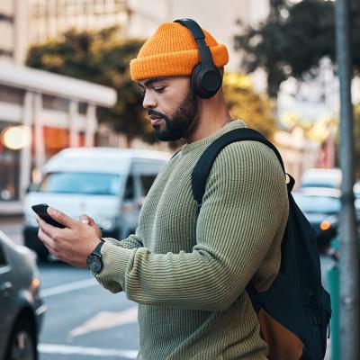 Man listening to music outdoors while about to cross a street.